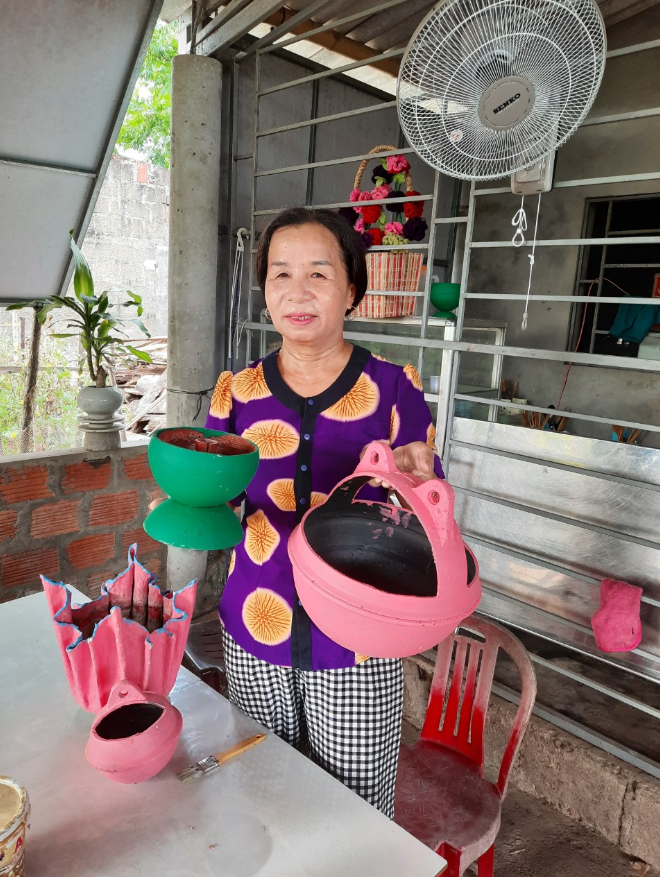 Bà Nguyễn Thị Hường bên chậu hoa được làm từ rác thải nhặt từ biển
