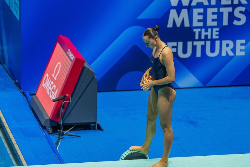 Diver Georgia Sheehan begins to step onto the diving board, looking down