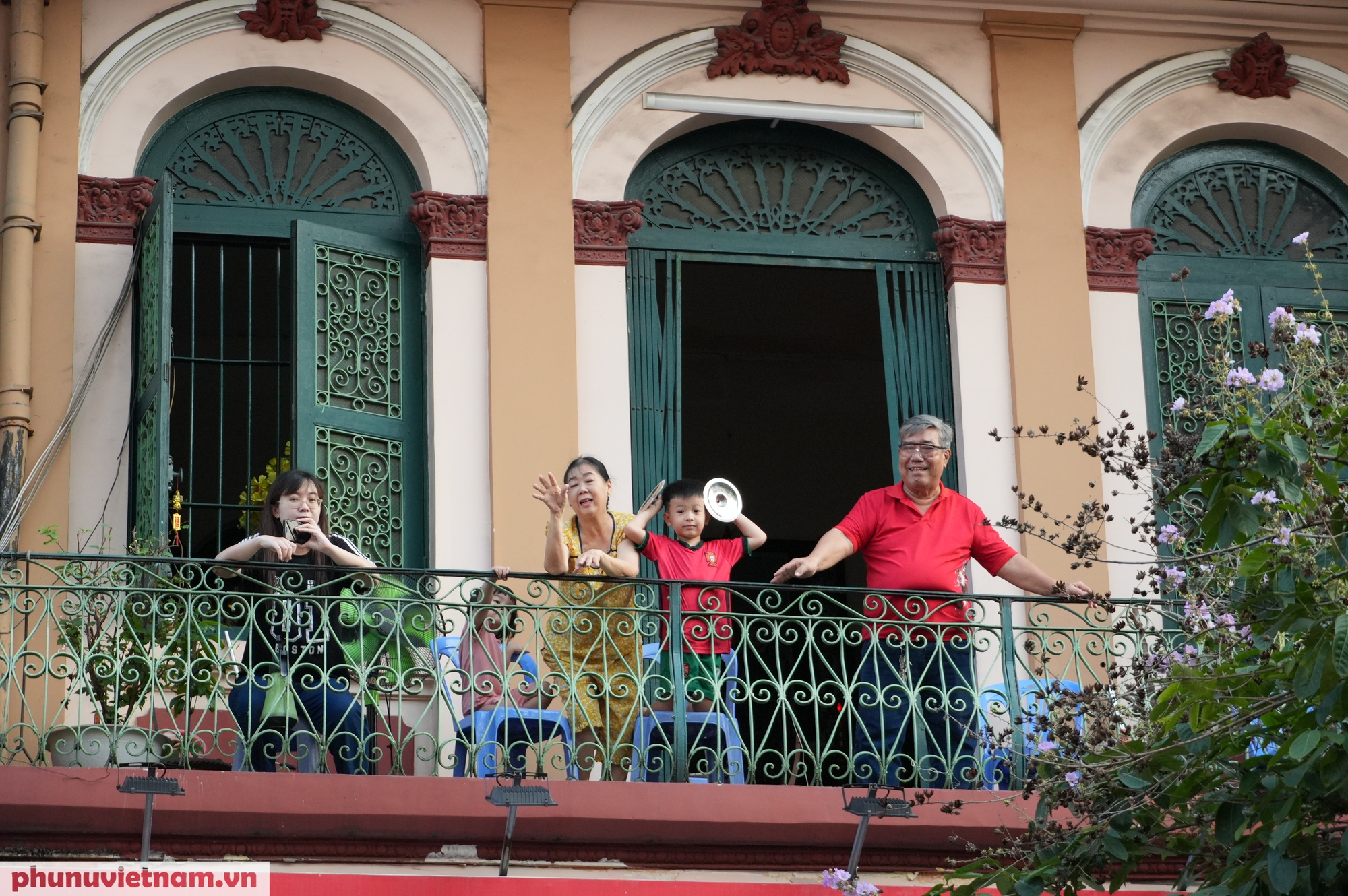 Một gia đình tại khu phố cổ người Hoa ra ban công chào đón đoàn diễu hành
