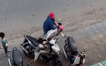 Khi vợ tiến tới chiếc xe máy, người chồng lao tới giật tóc, đá liên tiếp vào người.