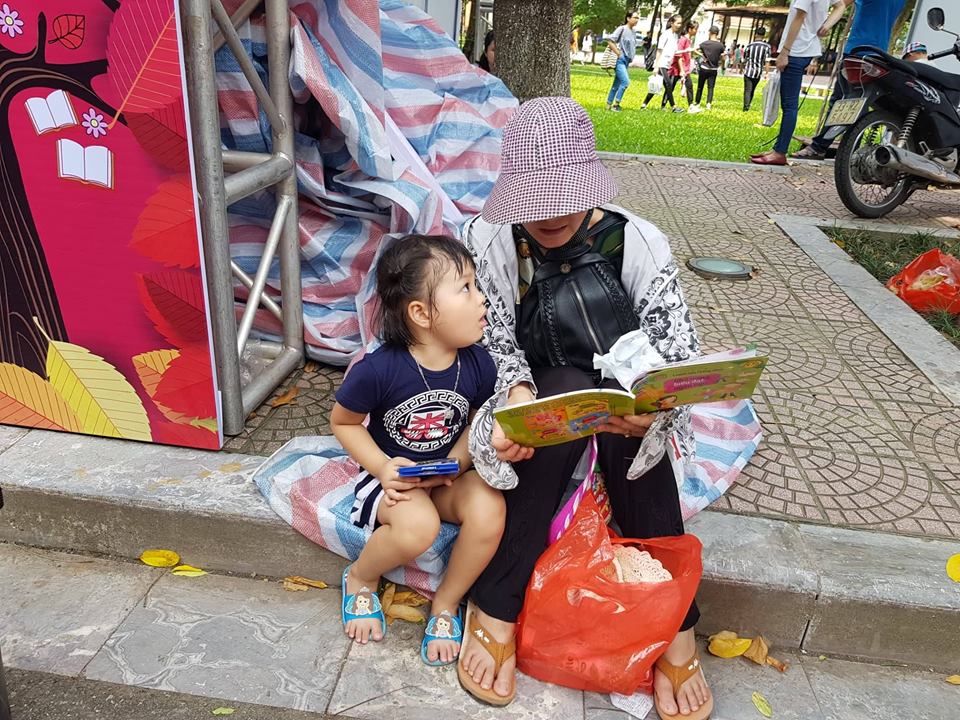 Vệ đường ngay công viên là nơi dừng chân đọc sách của bà và cháu. 