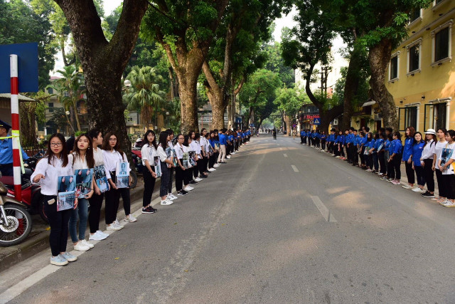 Tình nguyện viên, đoàn thanh niên cầm ảnh đồng chí Đỗ Mười đứng hai bên đường dọc Nhà tang lễ để tiễn đưa nguyên Tổng Bí thư.