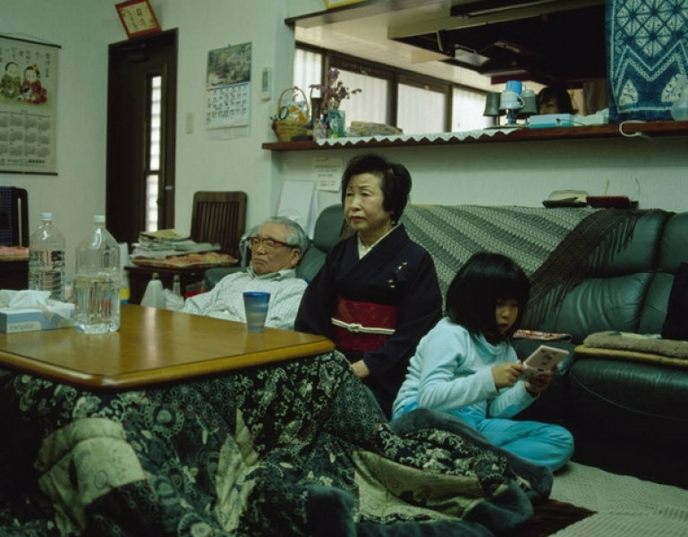 Hình ảnh gia đình truyền thống, có ông bà lặng lẽ xem ti vi. Trong khi đó người cháu gái ngồi xoay lưng lại ông bà và mải mê với chiếc điện thoại thông minh.