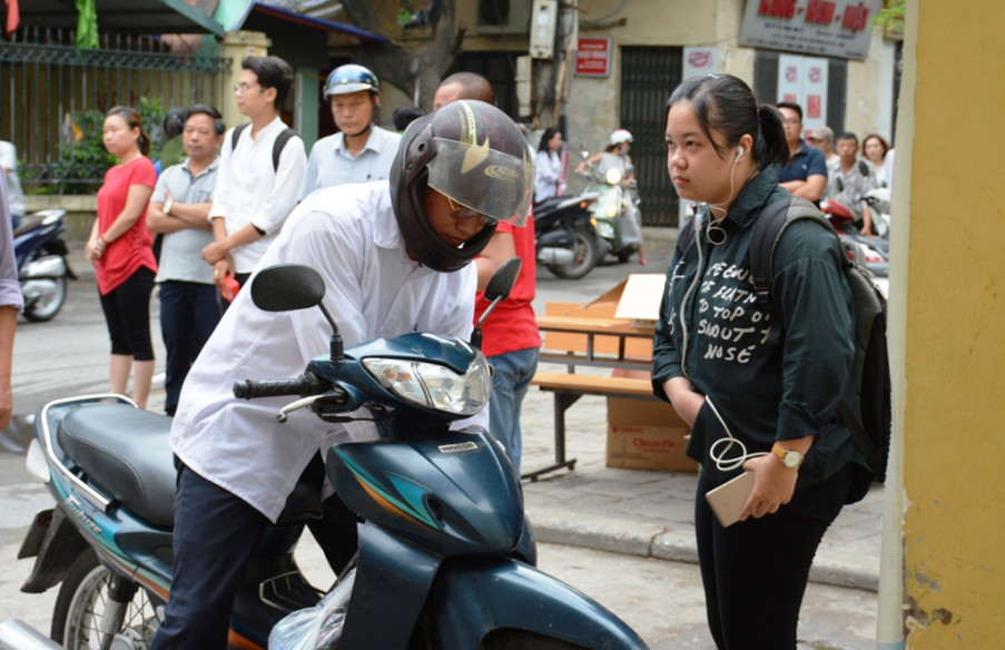 Một phụ huynh cẩn thận kiểm tra lại đồ đạc cho con gái, trước khi con bước vào phòng thi với gương mặt khá âu lo