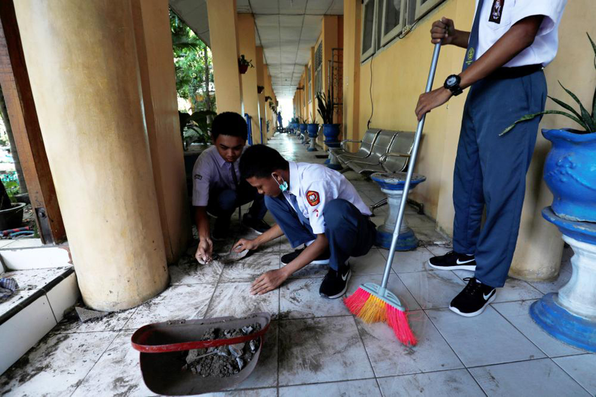 Trong những bộ đồng phục học sinh, các em bắt tay vào việc dọn dẹp lại lớp học của mình. 