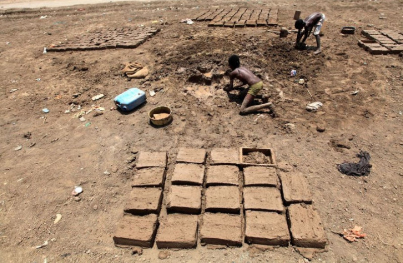 Giống như nhiều người ở vùng Darfur, cậu bé này đang phải kiếm sống bằng cách nặn bùn đất thành các viên gạch.