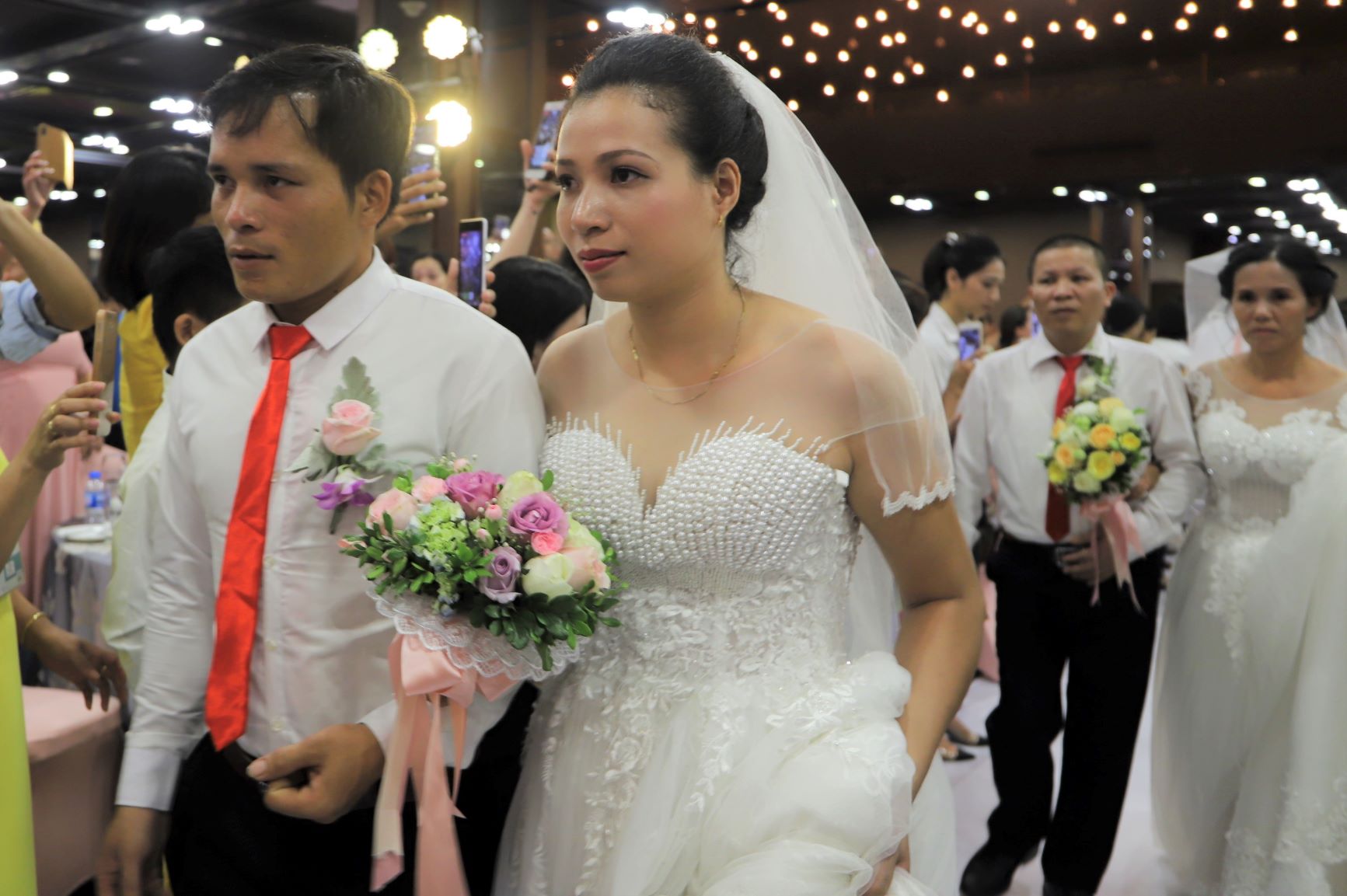 Ngay sau đó là lễ cưới, các cô dâu chú rể tay trong tay tiến vào lễ đường trong sự cổ vũ nồng nhiệt của người thân, bạn bè.