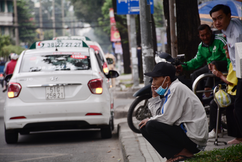 Một người đàn ông ngồi co ro trong lúc chờ xe buýt.