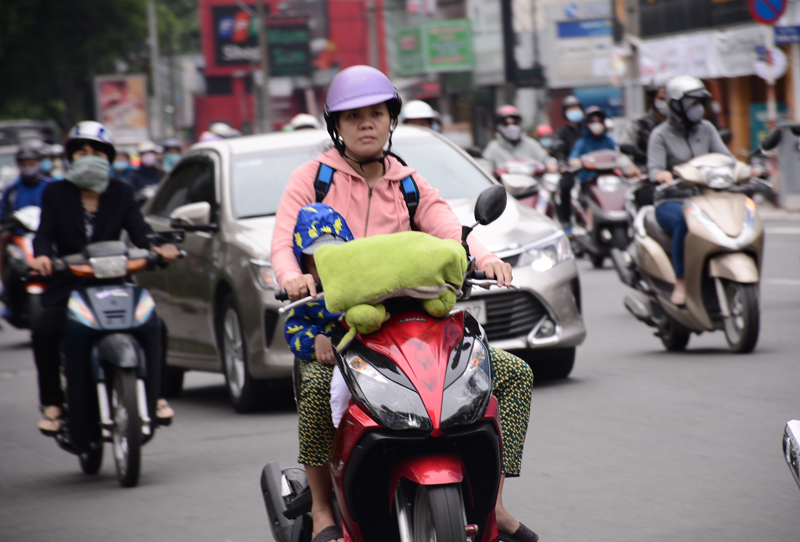 Một em bé được mẹ mặc ấm, gục ngủ trên xe máy vào sáng sớm ngày 20/12. Nhiều phụ huynh mặc cho con mình hai, ba lớp áo ấm, găng tay, mũ len… để chống lạnh