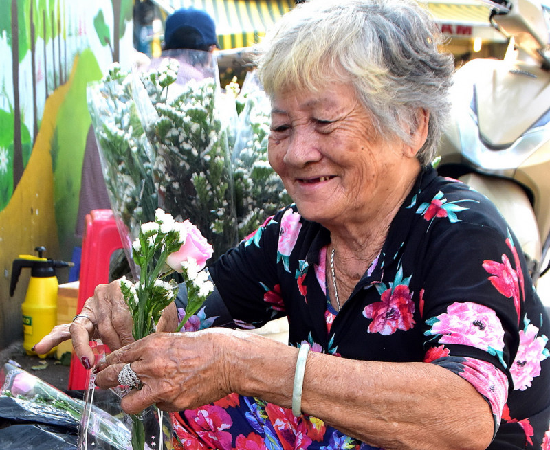 Một cụ bà đang cắm hoa bán trước chợ cho biết vừa qua lễ Valentine mua hoa vào nhiều quá nhưng bán không hết bị lỗ nên 8/3 này bán ít lại cho 