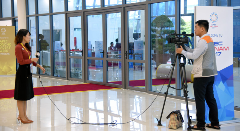 Nữ phóng viên dẫn chương trình truyền hình về hoạt động tại Tuần lễ cấp cao APEC. 