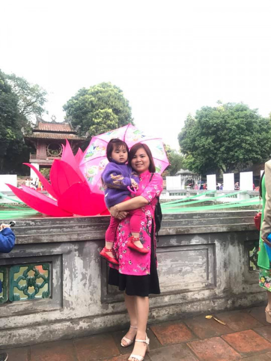 Người mẹ trẻ xúng xính áo dài che ô chụp ảnh cùng con gái.