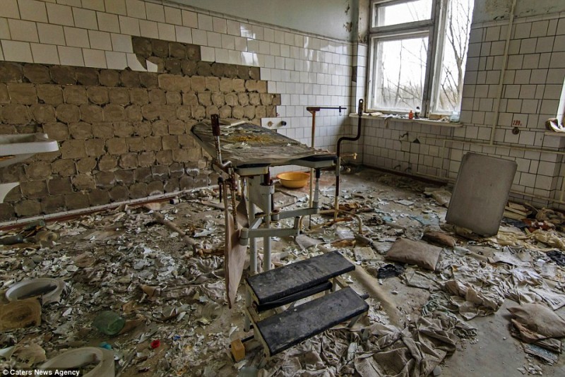 Một căn phòng điều trị tại bệnh viện bị đổ nát và tỏa ra mùi hôi thối. Chiếc bàn phẫu thuật ở giữa những mảnh vụn, đồ đạc cũ hỏng và gạch rơi ra khỏi bức tường.