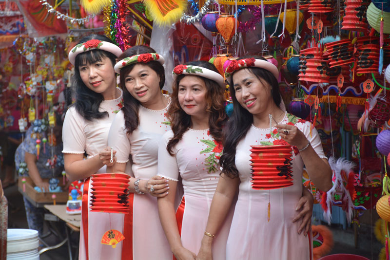 Một nhóm phụ nữ diện áo dài chụp hình kỷ niệm bên những chiếc lồng đèn đủ màu sắc.