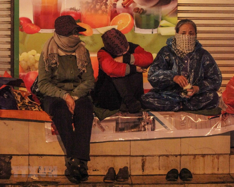 Người lao động co ro trong giá lạnh trên phố Tràng Thi, quận Hoàn Kiếm, đêm 28/12. 