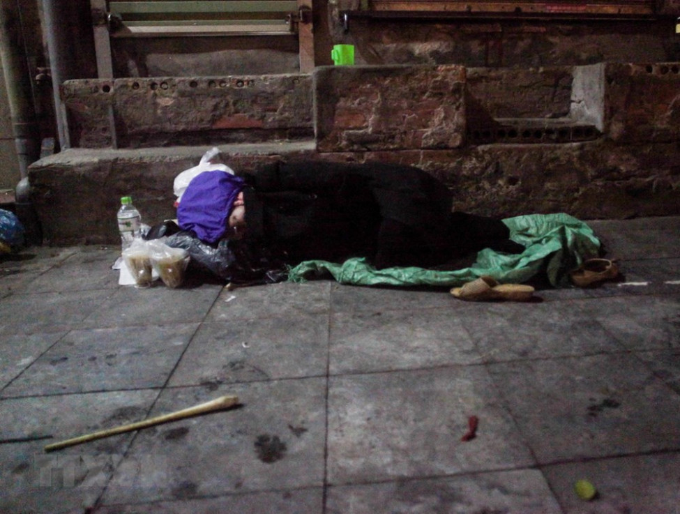 Một người vô gia cư co ro trong cái lạnh đêm 28/12 tại khu vực chợ Đồng Xuân, quận Hoàn Kiếm.