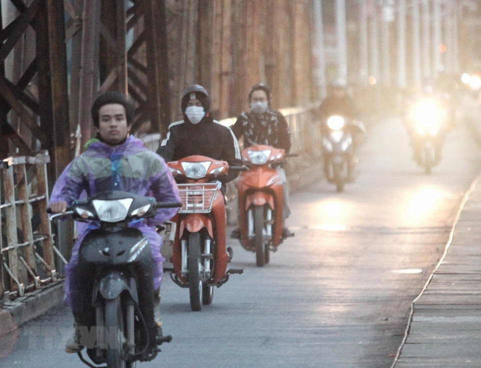 Người dân phải bịt khẩu trang, mặc áo mưa khi lưu thông qua cầu Long Biên sáng sớm 29/12. 