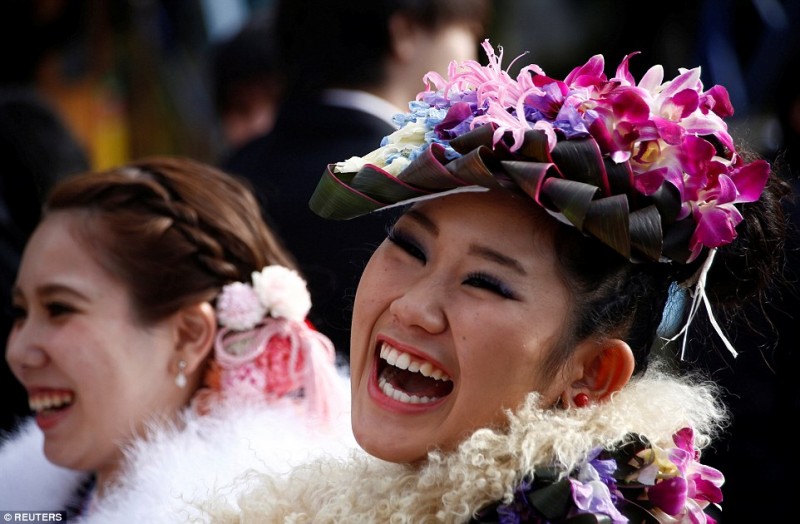 Một cô gái cười rạng rỡ với khuôn mặt được trang điểm kỹ lưỡng và kiểu tóc cầu kỳ được gắn những đóa hoa tươi. Trong ngày lễ trưởng thành, các thiếu nữ Nhật Bản thường chăm chút rất kỹ về ngoại hình của mình.