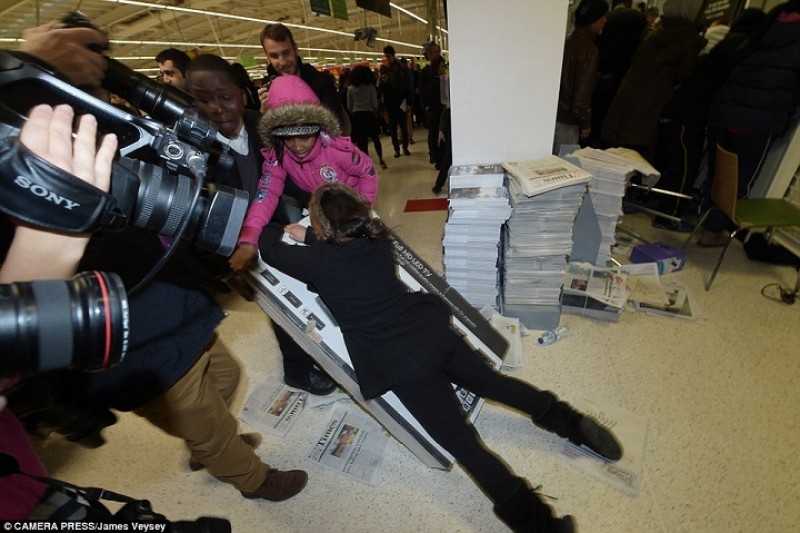 Một phụ nữ cố gắng nằm đè lên chiếc tivi sau khi cãi nhau tranh giành chiếc tivi này với những khách hàng khác tại 1 cửa hàng Asda ở Wembley, Anh.