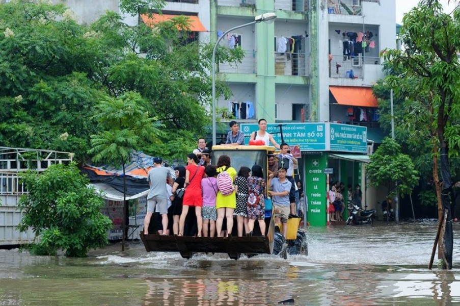 Váy ngắn, chân dài vượt mưa lũ đến công sở bằng máy xúc