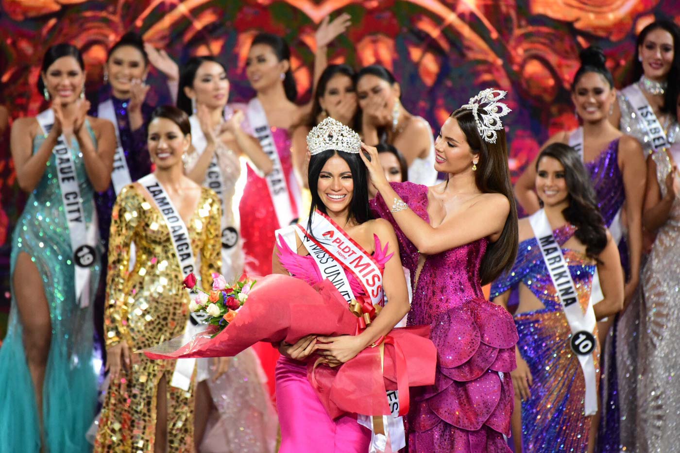 Đăng quang Hoa hậu Hoàn vũ Philippines 2019 là Gazini Christiana Ganados (23 tuổi). Cô sở hữu chiều cao 1,73m, tốt nghiệp Đại học San Jose-Recoletos, chuyên ngành du lịch. Trong ảnh, Gazini Christiana Ganados nhận vương miện từ người tiền nhiệm, cũng là đương kim Miss Universe - Hoa hậu Hoàn vũ Catriona Gray