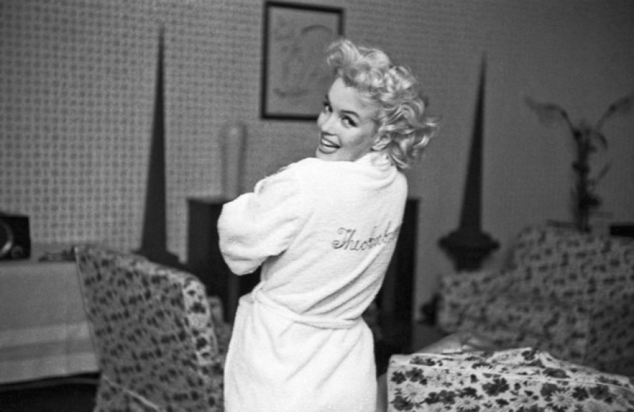 Marilyn Monroe tươi cười khoe chiếc áo tắm thêu chữ ký tên mình khi cô ở khách sạn Ambassador, New York vào năm 1955.