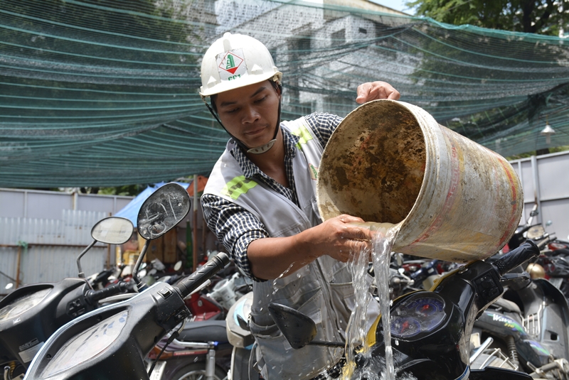 Một người gửi xe cố rửa đi lớp bùn đất dính trên xe trước khi đi sửa.