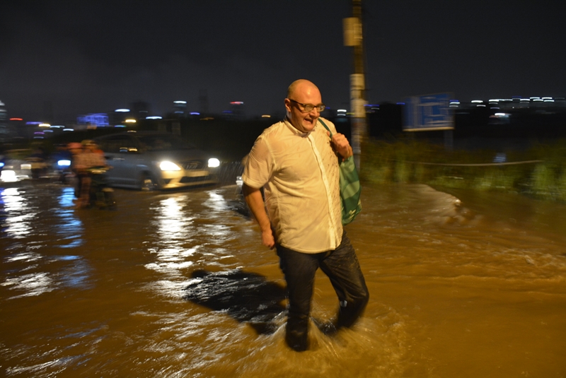 Một người đàn ông ngoại quốc băng qua con đường ngập nước.