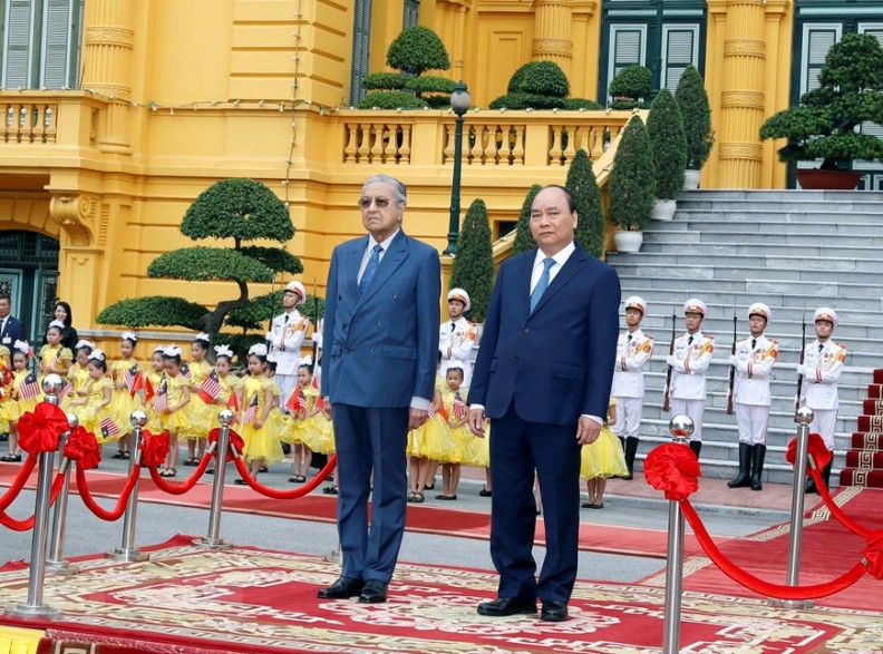 Thủ tướng Nguyễn Xuân Phúc và Thủ tướng Malaysia Mahathir Mohamad nghe quân nhạc cử Quốc thiều hai nước. (Ảnh: Thống Nhất/ TTXVN)