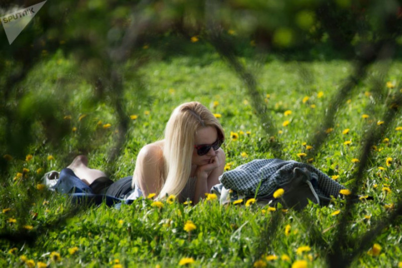 Một nữ thanh niên thư giãn trên thảm cỏ vườn táo ở đây.