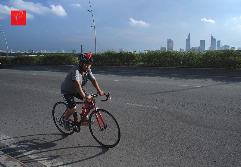 Một người cao tuổi thong thả đạp xe rèn luyện sức khỏe trên con phố thoáng đãng rộng rãi bên ngoài trung tâm 