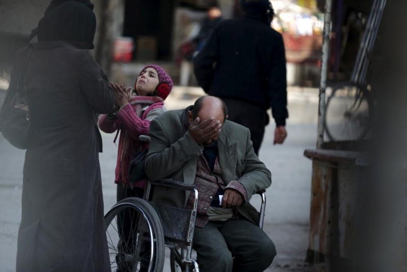 Một cô bé cùng cha ngồi trên chiếc xe lăn ăn xin để có tiền thanh toán viện phí ở Douma, Syria, ngày 3/2/2016.