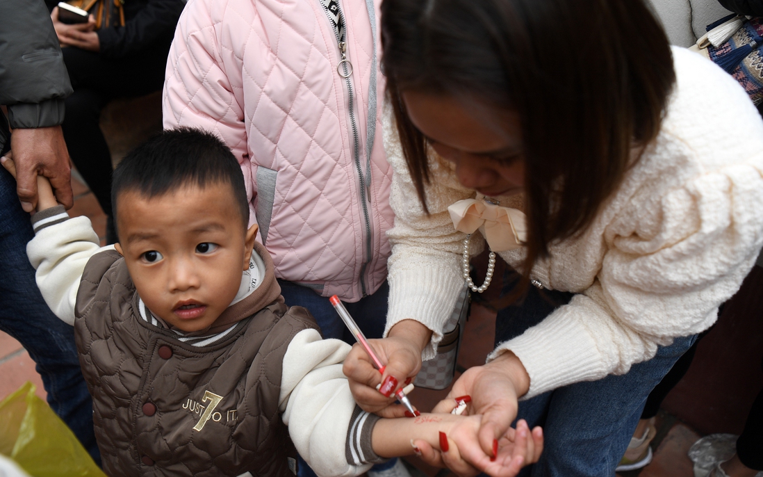Phụ huynh viết số điện thoại vào tay con nhỏ đề phòng đi lạc trong ngày khai hội Chùa Hương
