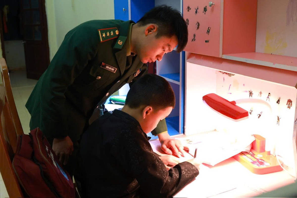 Cán bộ Đồn Biên phòng Lũng Cú đang hướng dẫn con nuôi của đơn vị ôn bài. Trong những năm qua, Đồn đã nhận đỡ đầu và nuôi dưỡng nhiều học sinh có hoàn cảnh đặc biệt khó khăn