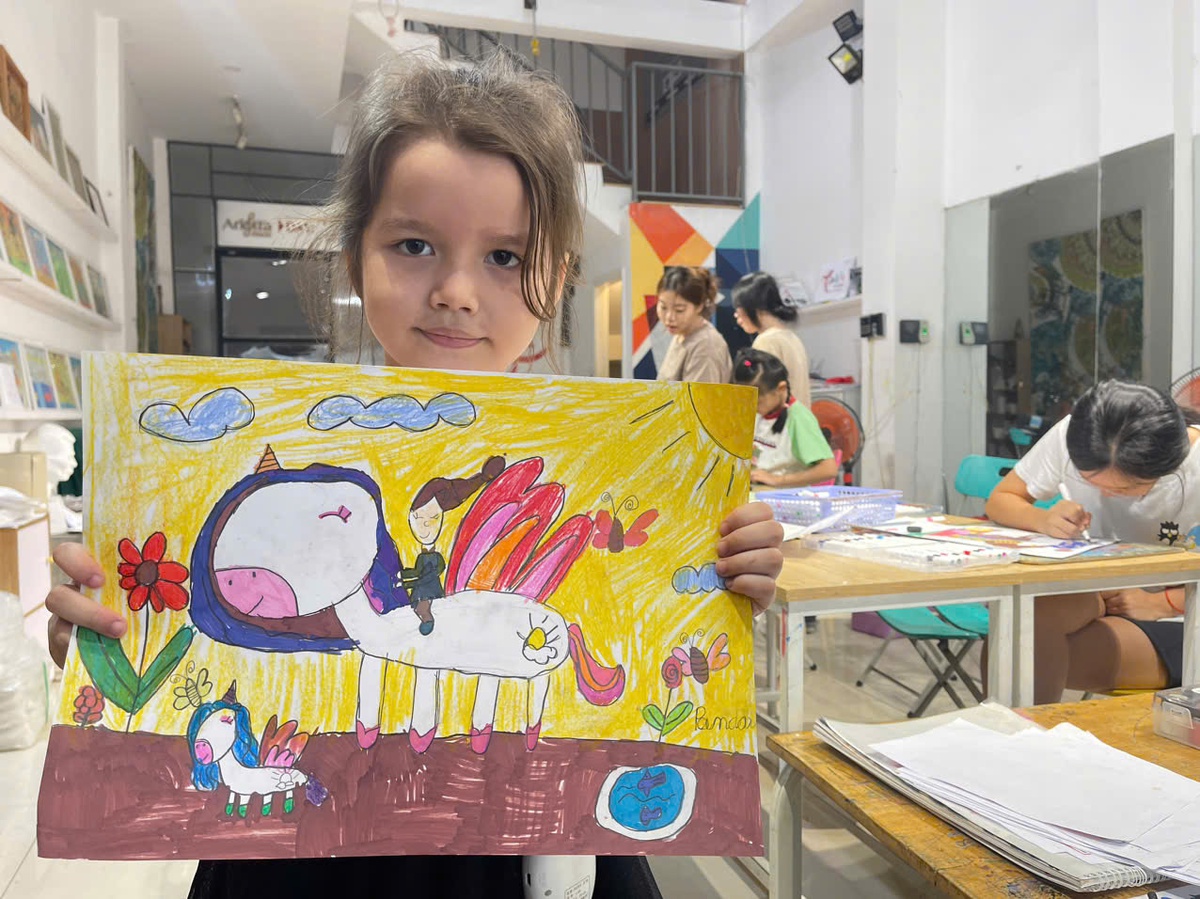 Bé Nguyễn Đoàn Nhật Hạ (sinh năm 2020) và tác phẩm được trưng bày tại triển lãm. Ảnh: NVCC