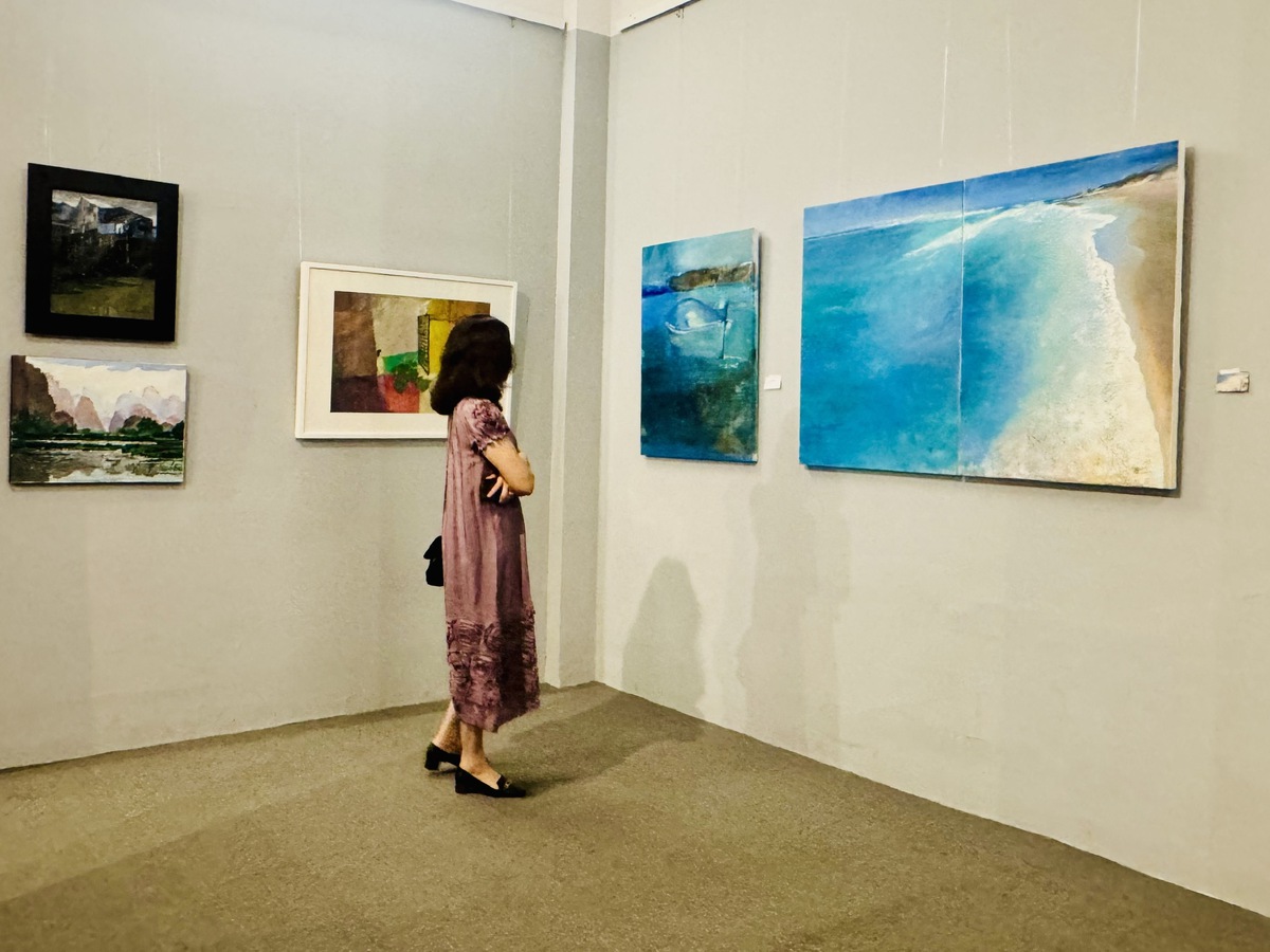 Người xem chăm chú thưởng thức các tác phẩm được trưng bày tại triển lãm. Ảnh: Hồ Lam