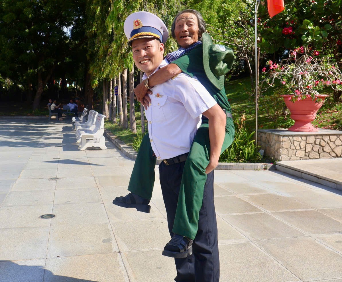 Một đồng chí cõng nhạc sĩ Đỗ Lập xuống bậc thềm sau khi ông viếng thăm Khu tưởng niệm chiến sĩ Gạc Ma. Ảnh: Hồ Lam