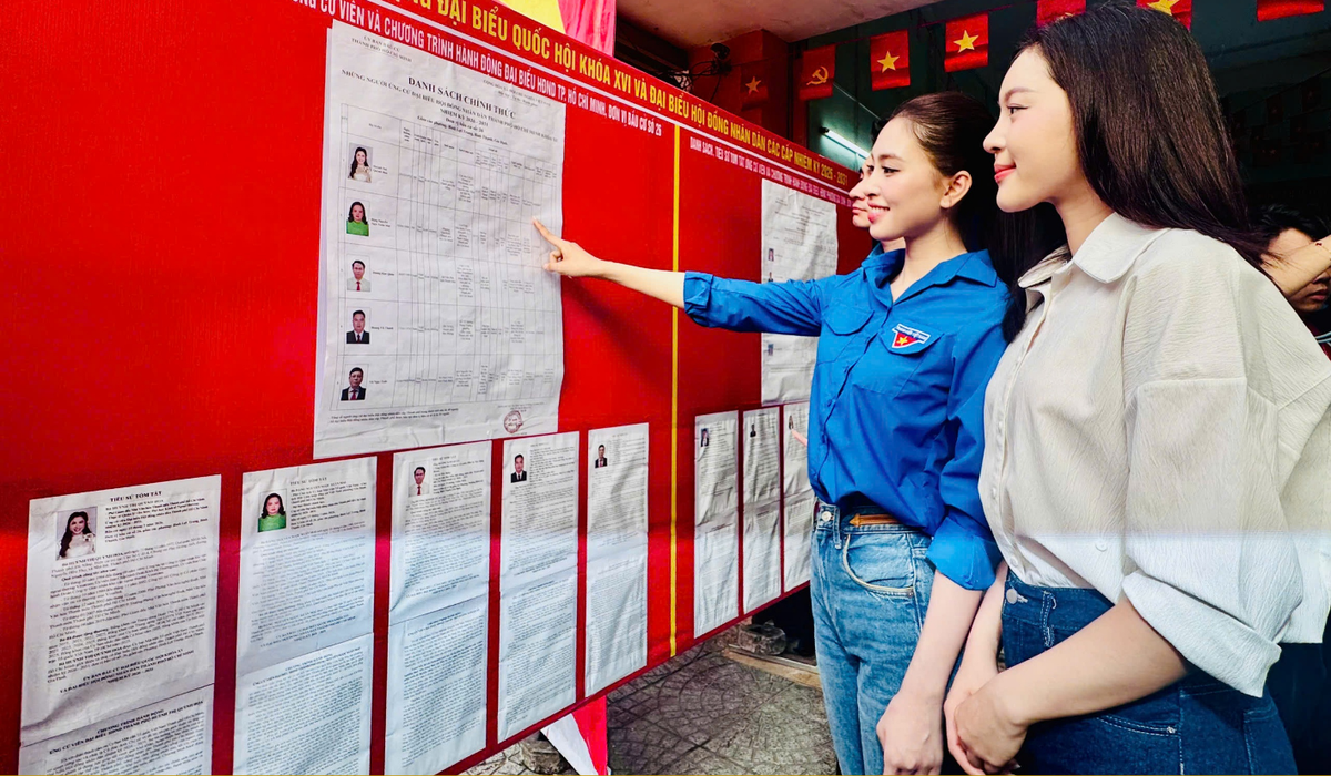 Hoa hậu Trần Tiểu Vy (thứ 2 từ phải sang) xem tiểu sử tóm tắt của các ứng cử viên tại điểm bỏ phiếu số 28 thuộc phường Gia Định, TPHCM, trước khi bỏ phiếu          Ảnh: Hồ Lam