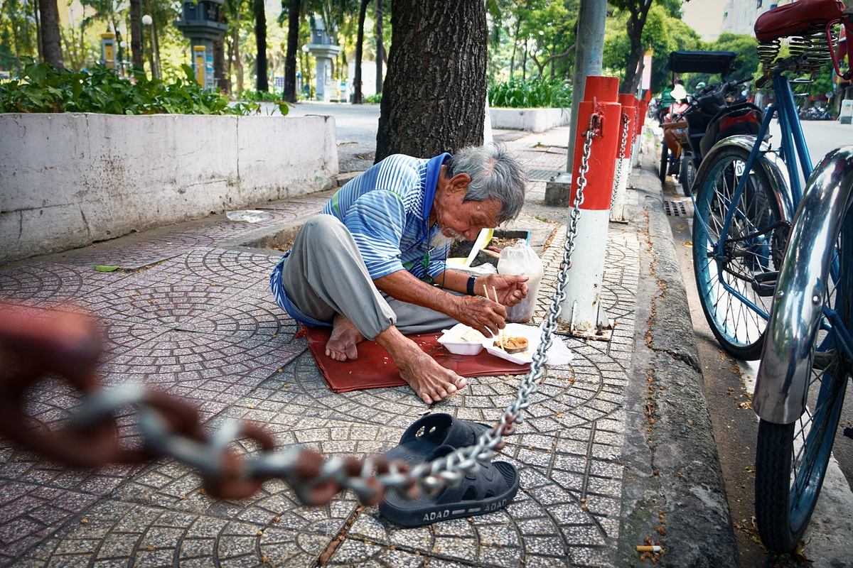 Chú Tư 80 tuổi đạp xích lô tranh thủ ngồi ăn trưa dưới vỉa hè công viên 23/9