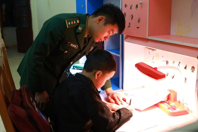 Cán bộ Đồn Biên phòng Lũng Cú đang hướng dẫn con nuôi của đơn vị ôn bài. Trong những năm qua, Đồn đã nhận đỡ đầu và nuôi dưỡng nhiều học sinh có hoàn cảnh đặc biệt khó khăn
