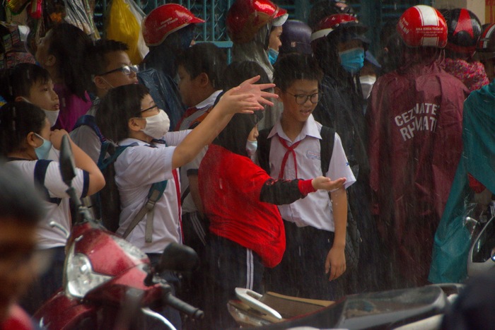 Các học sinh bị kẹt tại cổng trường vì mưa