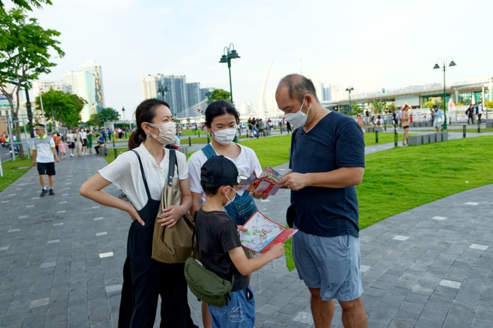 Một gia đình khsach du lịch người nước ngoài đang xem bản đồ để định vị trong lúc ngoạn cảnh ở công viên