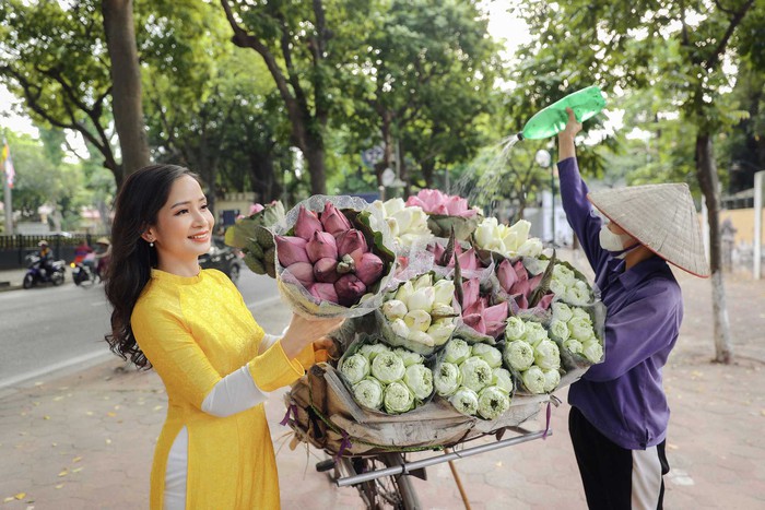 Nổi bật với chiếc áo dài màu vàng, Vũ Diệu Thảo sang trọng, quý phái khi tự tay mình chọn những bó sen từ gánh hàng hoa trên phố phường Hà Nội