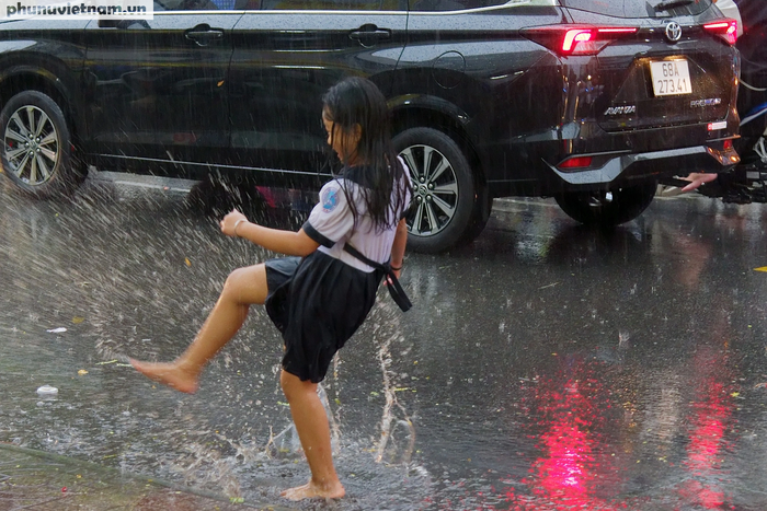 Một bé gái thích thú nghịch nước giữa cơn mưa, một cảm giác chung của nhiều người khi cơn mưa bất ngờ giải tỏa cảm giác nóng bức những ngày qua