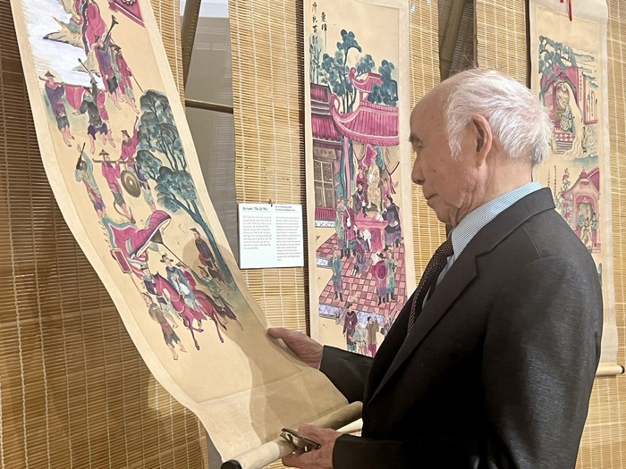 Họa sĩ Phạm Ngọc Khuê bên một tác phẩm trưng bày tại Triển lãm