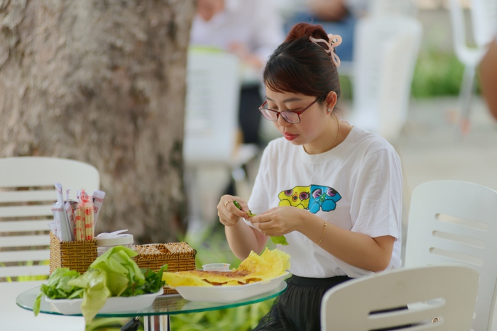 Một thực khách thưởng thức món bánh xèo được chế biến bắt mắt tại không gian ẩm thực