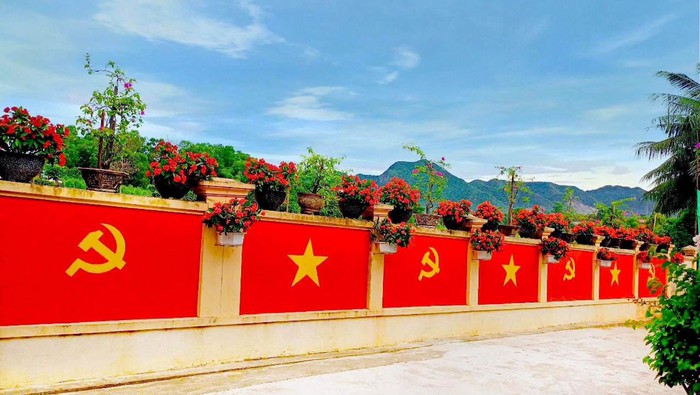 Đôi vợ chồng trẻ biến bờ tường cũ thành "con đường cờ" rực đỏ - Ảnh 1. Đôi vợ chồng trẻ biến bờ tường cũ thành "con đường cờ" rực đỏ - Ảnh 1.
