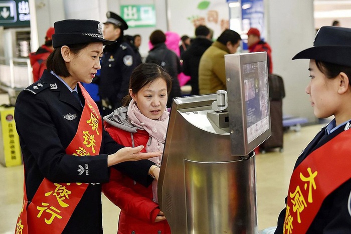Nhân viên đường săt hướng dẫn một hành khách cách mua vé bằng máy nhận dạng khuôn mặt