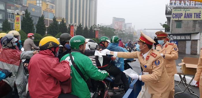 Trời mưa lất phất, người tham gia giao thông phải mặc áo mưa khi di chuyển, nhưng các chiến sĩ vẫn đứng ngoài đường phát khẩu trang miễn phí cho người dân.