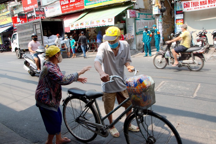 Một đôi vợ chồng già chở nhau bằng xe đạp đến nhận cơm từ thiện
